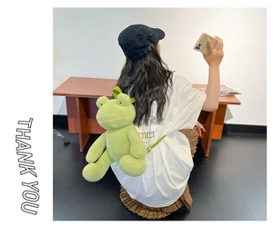 Close-up of cute green plush frog backpack with soft adjustable shoulder straps on model