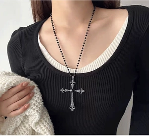Detail of gothic silver cross pendant with vintage texture on a black beaded chain necklace