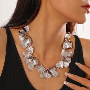 Close-up of oversized silver textured flower petal necklace on model collarbone