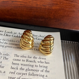 Detailed view of golden spiral textured square earrings with polished metallic finish