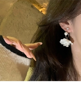 Dettaglio di orecchini floreali con perle su un'elegante modella femminile in posa