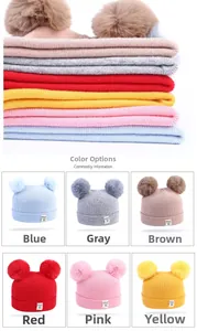 Detail showing various colors of knitted baby beanies with dual fluffy pom-poms