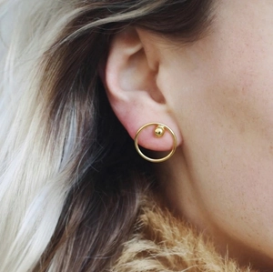 Detail view of gold geometric hoop earrings with a small bead on a female model