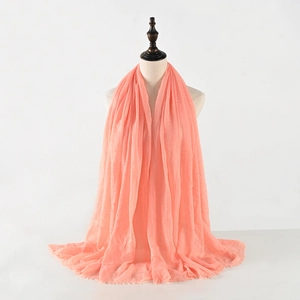 Detail shot of the coral cotton linen scarf featuring soft pleats and frayed edges on a model