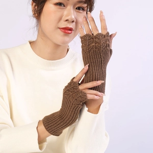 Detailed knit pattern on brown fingerless gloves worn with a white cozy sweater