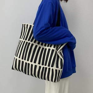 Detailed view of black and white striped canvas tote bag on model shoulder with zipper