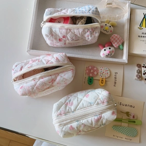 Gros plan de trousses de maquillage matelassées à fleurs avec étiquettes sur plateau