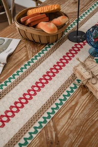 Close-up of woven cotton linen table runner with red and green geometric patterns