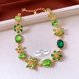 Close-up of vintage gold flower pendant with emerald green crystals and sparkling diamonds