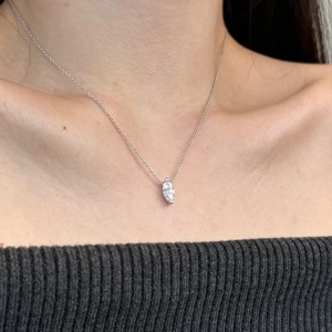 Macro shot of a marquise-cut zircon pendant on a silver chain worn by a female model