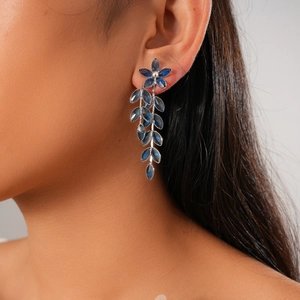 Detail of vintage silver earrings with dark blue glass flower petals and leaf tassel