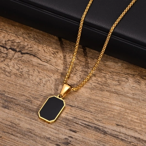 Detail of a men's gold rectangle pendant with black inlay on wood and leather background