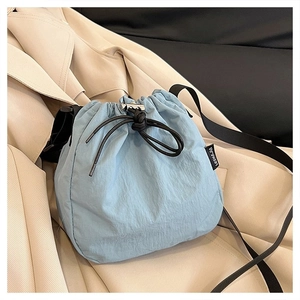 Detail of light blue nylon bucket bag with black drawstring closure and branded side label