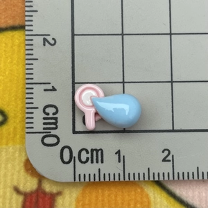 Close-up of a mini pink and blue resin charm on a scale showing 1.5cm size details
