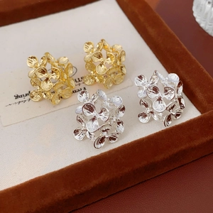 Macro view of gold and silver floral cluster stud earrings on a velvet display tray