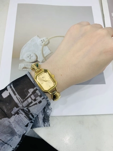 Dettaglio di un orologio al quarzo dorato rettangolare con cinturino a morsetto su rivista