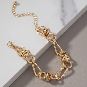 Golden chunky chain bracelet for men with irregular links on white marble background