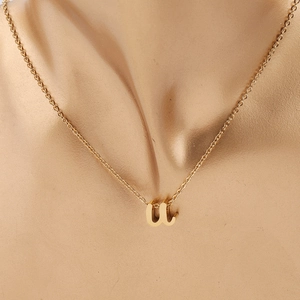 Gros plan d'un collier doré en acier inoxydable avec pendentif lettre w minuscule
