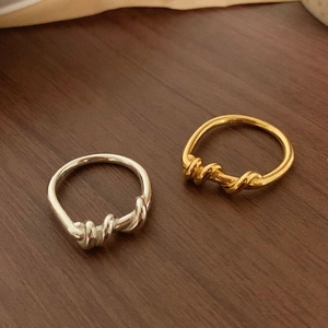 Minimalist twisted rope rings in gold and silver set on a rustic wood background