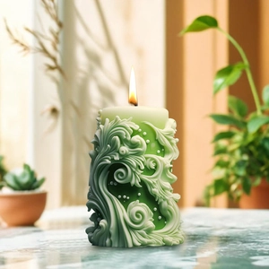 Vela aromática cilíndrica verde con tallado en relieve y una llama encendida