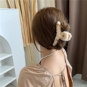 Gros plan d'une pince à cheveux en peluche camel sur un chignon bas au style minimaliste