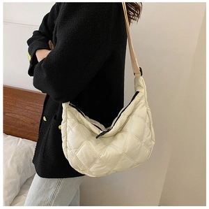 Close-up of beige quilted crossbody bag showing soft texture and diamond stitching details
