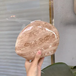 Close-up of pebble-shaped marble pattern clutch with glossy resin finish and top closure