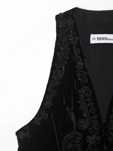 Detailed close-up of exquisite floral embroidery on the black velvet vest neckline