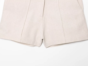 Dettaglio degli shorts in lino beige che mostra la trama naturale e la finitura del tessuto