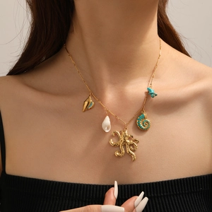 Detail of gold bamboo chain necklace with octopus shell and turquoise stone charms