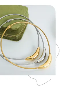 Detail of gold and silver curved pendant snake chain necklaces on green velvet