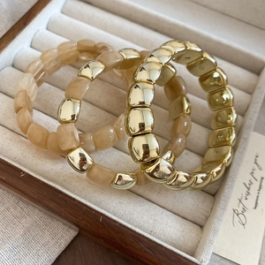 Close-up of a 3-piece set elastic chain bracelet with gold metal and marble resin textures