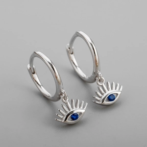 Gros plan de créoles œil porte-bonheur en argent avec cristaux bleus de style luxe