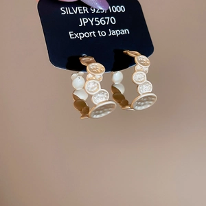 Close-up of irregular textured C-shaped silver stud earrings with 925 stamp in matte gold