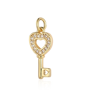Detail of a golden heart-shaped key pendant with zircon inlay and hollow carvings