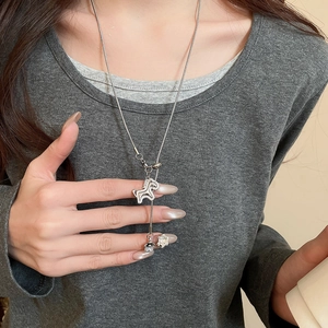 Detail of silver Y-shape necklace featuring zircon horse and flower charms on snake chain
