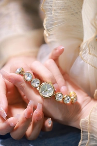 Gros plan d'une montre dorée pour femme avec bracelet à cristaux ronds et cadran quartz