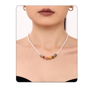 Detail of freshwater pearl necklace with multi-colored gemstone cubes and gold hoop earrings