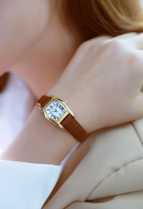 Brown leather rectangular watch with golden case and Roman numerals on a model's wrist