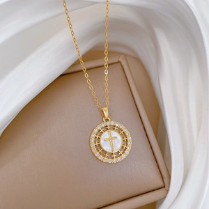 Detailed shot of gold cross necklace with shell inlay and cubic zirconia on silk
