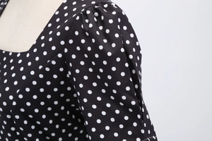 Detailed close-up of retro white polka dots on black fabric with puff sleeve stitching