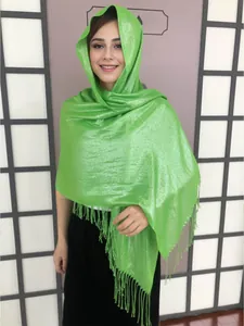 Detail of emerald green shawl with metallic shimmer and long tassels in headscarf style