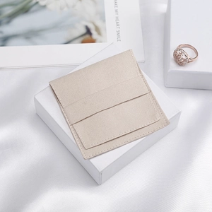 Detail of beige microfiber jewelry pouch with flap closure and white square gift box
