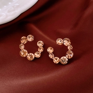 Détail des boucles d'oreilles en cristal champagne sur un tissu de satin rouge élégant