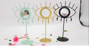 Three eye-shaped jewelry organizers with mirrors in green, gold, and black metal finishes