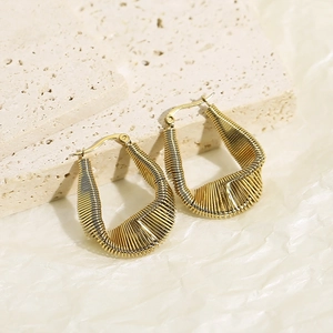 Détail de boucles d'oreilles torsadées dorées avec texture nervurée et forme de larme