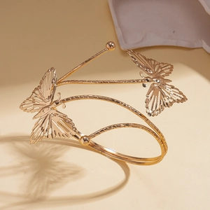 Détail du bracelet papillon ajouré doré avec des textures d'ailes gravées complexes