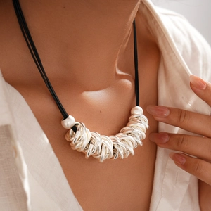 Close-up of layered black cord necklace with silver geometric circular rings on neck