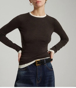 Detail of wool-knit top with white contrast edging on dark brown slim-fit sleeves
