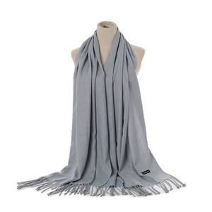 Close-up of gray cashmere scarf with tassel details and material label on mannequin